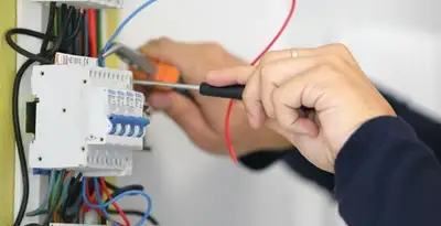 Electrician installing and adjusting circuit breakers in an electrical panel in Bellevue, NE